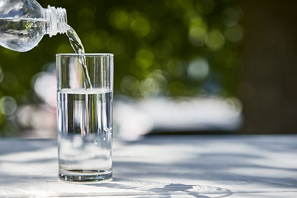Fresh clean water pouring from bottle in transparent glass